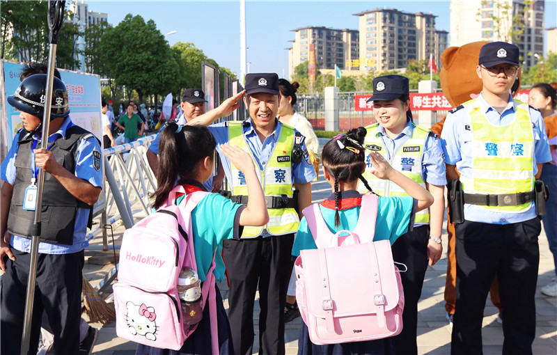 插圖兩名小學(xué)生與護學(xué)民警相互敬禮。