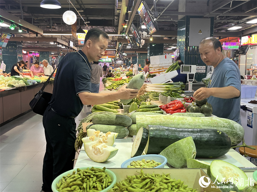 晚高峰時(shí)段，一名背著公文包的男士路過(guò)洪山廣場(chǎng)地鐵站菜市場(chǎng)買菜。人民網(wǎng)記者 張雋攝