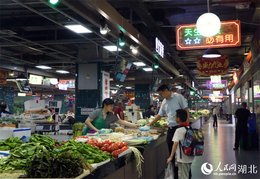 下班后，家長(zhǎng)接到孩子，順便在地鐵菜市場(chǎng)買個(gè)菜。人民網(wǎng)記者 周恬攝