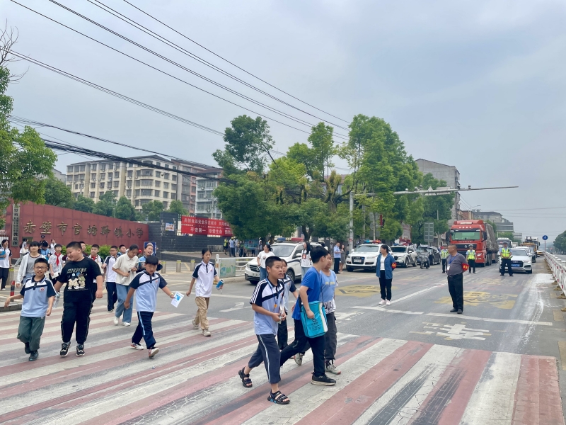 官塘驛中隊(duì)交警截停車流，形成安全屏障，守護(hù)小學(xué)生上放學(xué)路。